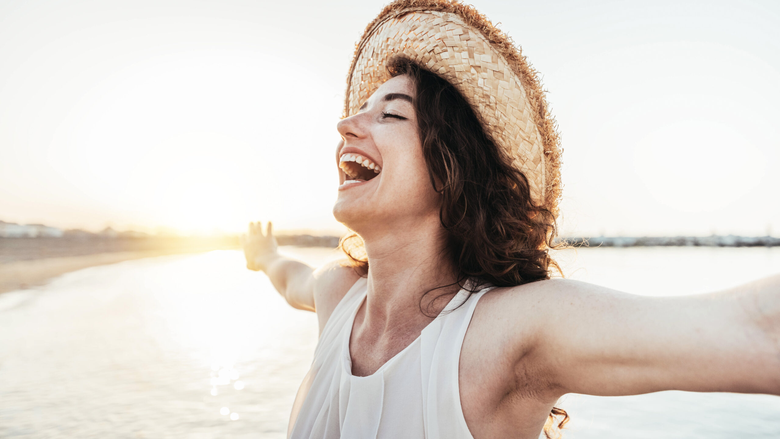 Happy woman with arms outstretched enjoying freedom at the beach